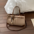 Dettaglio della borsa tote intrecciata con finiture in pelle marrone e ciondolo - Caffè senza Ciondolo