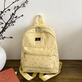 Zaino giallo chiaro con stelle d'argento e logo nero su un tavolo di legno - Giallo