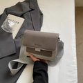 Bolso bandolera gris bicolor con correa ancha de tela sobre un fondo de estilo minimalista - gris oscuro