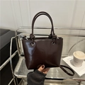 Bolso cubo de cuero brillante marrón oscuro con asa anudada y forma trapezoidal - Marrón