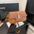 Brown leather and woven crossbody bag with a golden geometric buckle held by hand - Brown