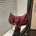 Retro pleated burgundy shoulder bag with large metal buckle shown in hand display - Red