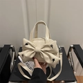 Creamy beige square crossbody bag featuring a large bow and black star rivets - White