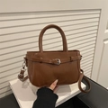Brown faux leather handbag with buckle detail and detachable strap on white book - Brown