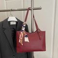Retro weinrote Tragetasche mit Seidenschal-Detail vor einem schwarzen Blazer-Hintergrund - Rot