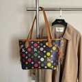 Black tote bag with colorful letters and brown leather straps on a coat rack - Black
