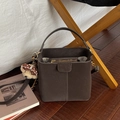 Dunkelbraune Beuteltasche mit Tragegriff und Plüschbär-Anhänger auf Vintage-Stuhl - Mit Anhänger / Braun