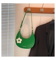 Gros plan d'un sac demi-lune en cuir vert émeraude avec un pendentif fleur blanche - Vert