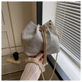 Detailed shot of woven bucket bag featuring gold chain and decorative pearl drawstrings - Gray