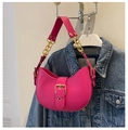 Detalle de bolso medialuna rosa con cadena dorada sobre fondo de chaqueta vaquera - Rosa Rojo