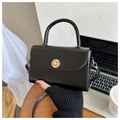 Nahaufnahme der schwarzen Ledertasche mit goldenem Drehverschluss mit Sonnenstrahl-Muster - Schwarz