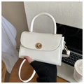 Detail einer cremeweißen Handtasche mit goldenem Drehverschluss und festem Tragegriff - Weiß