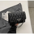 Chic black quilted crossbody bag with diamond pattern and metal chain strap on grey blazer - Black