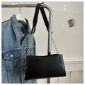 Detalle de bolso bandolera de cuero negro mate con cadena dorada en una percha - Negro