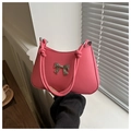 Detail der rosa Handtasche mit silberner Metallschleife und speziell geknotetem Tragegriff - Rosa