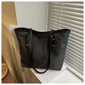 Detail of black matte large tote bag with golden rivets near a shuttered window - Black