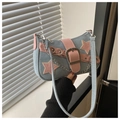 Detail of blue denim shoulder bag featuring pink star patches and a silver metal chain - Light Blue