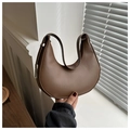 Detail view of the brown leather crescent bag featuring a metallic buckle and curved profile - Brown