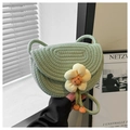 Dettaglio di borsa a tracolla intrecciata verde chiaro con un fiore decorativo in tessuto - Verde