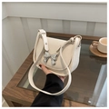 Detail of a creamy white leather bag featuring a shiny silver metal bow decoration - Off White