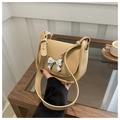 Detail view of a beige crossbody bag featuring a silver bow-knot hardware accent - Khaki