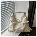 Cream white hobo bucket bag with bow accents and letter print on a sunny windowsill - White