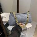 Gray matte underarm bag with chunky gold chain strap held by a person in a stylish setting - Blue