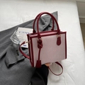 Bolso tote bicolor rosa y burdeos con correa ajustable y colgante sobre un traje gris - Burdeos