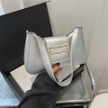 Chic silver baguette underarm bag with golden metallic clasp on elegant studio background - Silver