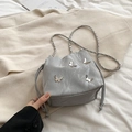 Light gray bucket bag with silver butterfly charms and chain strap on knitwear - Silver