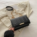 Classic black quilted crossbody bag with golden chain strap on a white blazer - Black