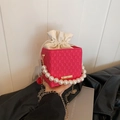 Magenta drawstring bucket bag with checkered texture, pearl handle, and gold chain strap - Pink