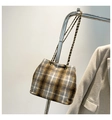 Détail d'un sac à carreaux en laine avec chaîne dorée à côté d'un blazer gris - Grille Grise