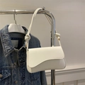 Borsa a spalla minimalista in pelle bianca con patta a onde e nodi su una giacca di jeans - Bianco