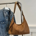 Brown suede hobo bag with fringe zipper detail and adjustable strap hanging on a rack - Brown