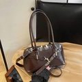 Deep brown glossy Boston tote bag with adjustable strap on a classic trench coat - Brown