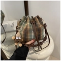 Detail of plaid bucket bag with plush fabric texture, drawstring, and monster charm - Green (With Pendant)