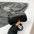Glossy black patent leather shoulder bag with gold lettering and knotted strap detail - Black