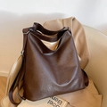 Große dunkelbraune Vintage Hobo Tasche mit breitem Gurt auf einem Ledersessel - Braun