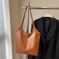 Borsa a spalla minimalista in ecopelle marrone caramello mostrata in un set elegante - Marrone