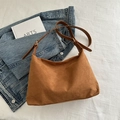 Bolso hobo retro de ante marrón con correa ajustable sobre fondo de mezclilla - Marrón