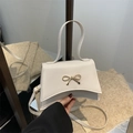 White trapezoid crossbody bag with golden bow buckle and slim adjustable strap - White
