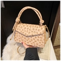 Close-up of cream square bag with embossed clover pattern and knotted handle detail - Khaki