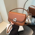 Handtasche in Karamellbraun mit Herzschloss, zeigt Größe in der Hand mit Schultergurt - Braun