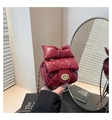 Detail of red quilted mini bag featuring a large bow and golden circular twist lock - Red