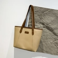 Bolso tote beige de gran capacidad con asas marrones y etiqueta de moda sobre roca - Caqui