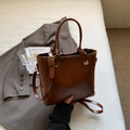Detalle del bolso tipo cubo marrón vintage con asa anudada y elegantes herrajes dorados - Marrón