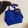Bolso tote de lona azul real con bolsillo frontal y costuras blancas en contraste - Azul