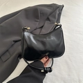 Glossy black crescent shoulder bag with knot strap and gold metal details - Black