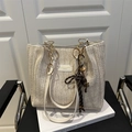 Bolso tipo cubo trenzado beige chic con asas de cuero y cadena dorada sobre silla - Sin colgante / Blanco